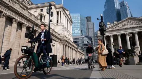 Getty Images Un hombre de traje recorre en bicicleta la ciudad de Londres con el edificio del Banco de Inglaterra detrás de él.