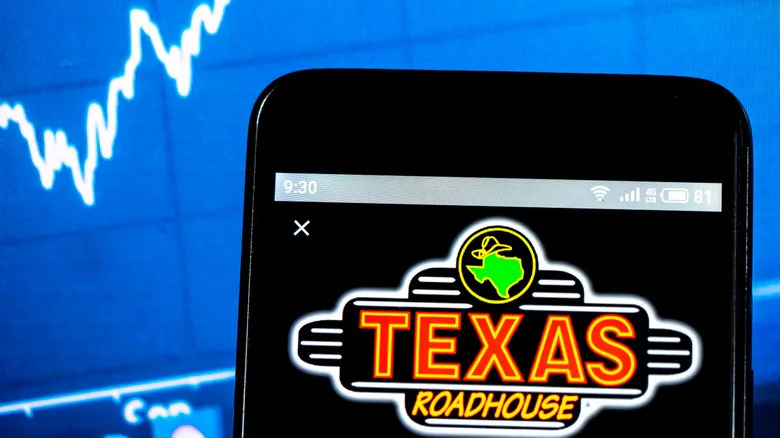 El logotipo de Texas Roadhouse en el teléfono con un gráfico ascendente de fondo