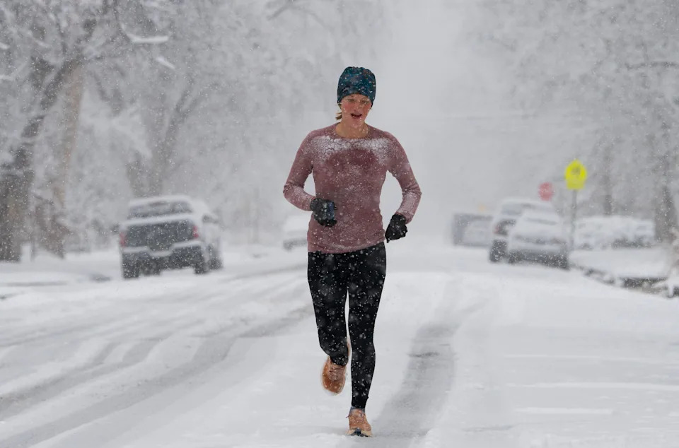 Una mujer corre en medio de una calle durante una tormenta de nieve.