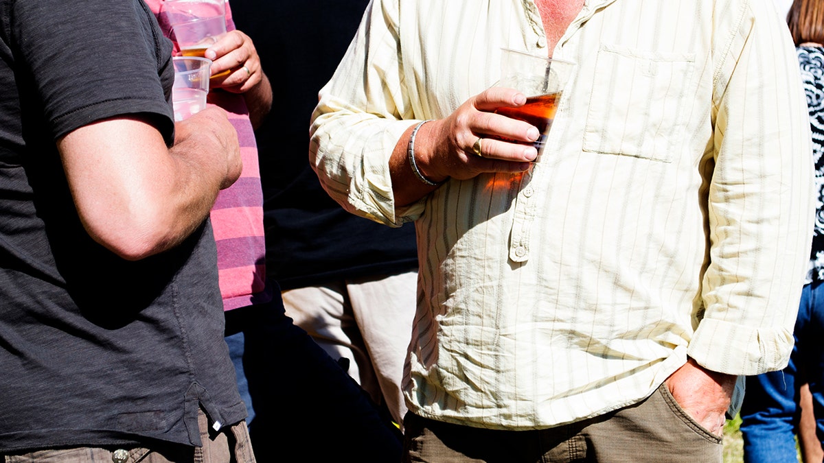 3 hombres en un festival de verano bebiendo cerveza en vasos de plástico
