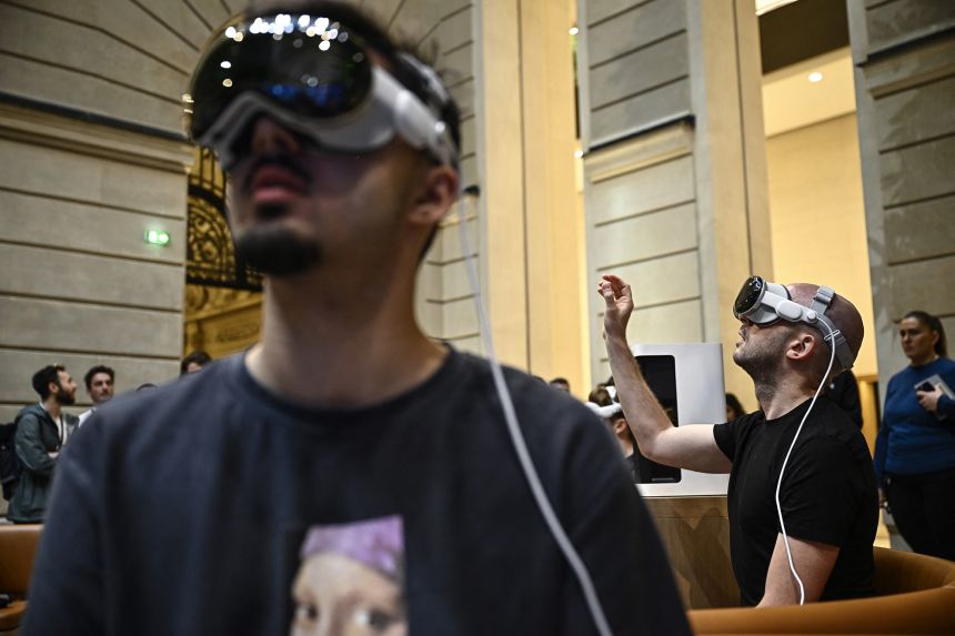 Los clientes prueban el dispositivo de gafas de realidad mixta Apple Vision Pro de la empresa estadounidense Apple Inc. durante el lanzamiento en la tienda Apple de la avenida de los Campos Elíseos de París el 12 de julio de 2024.