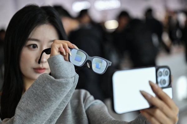 Esta fotografía tomada el 13 de noviembre de 2025 muestra a una mujer revisando un par de gafas Rokid con pantalla y cámara usando inteligencia artificial (IA) y realidad aumentada (AR) durante un evento de presentación en Hangzhou, provincia de Zhejiang, en el este de China. En China, las gafas con inteligencia artificial permiten a los usuarios pagar en las tiendas con solo echar un vistazo a un código QR y un comando de voz, a medida que un número creciente de empresas buscan conquistar los crecientes mercados nacionales y extranjeros. El interés por las gafas inteligentes está aumentando en todo el mundo después de más de una década de promesas estancadas, y los avances en inteligencia artificial están despertando un renovado interés en el sector. (Foto de Héctor RETAMAL/AFP vía Getty Images)