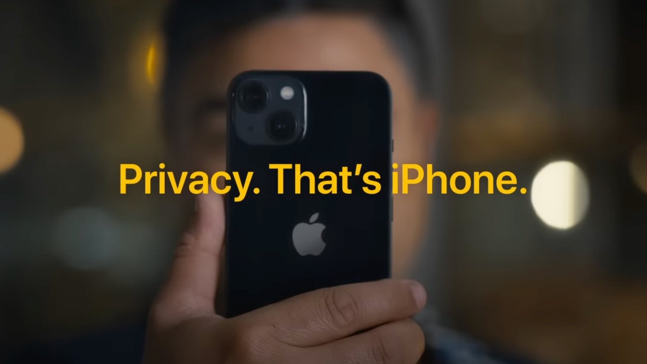 Una persona que sostiene un iPhone negro cerca de su cara por la noche con luces borrosas de la ciudad en el fondo y un texto amarillo en negrita que dice Privacidad. Ese es el iPhone alrededor del centro.