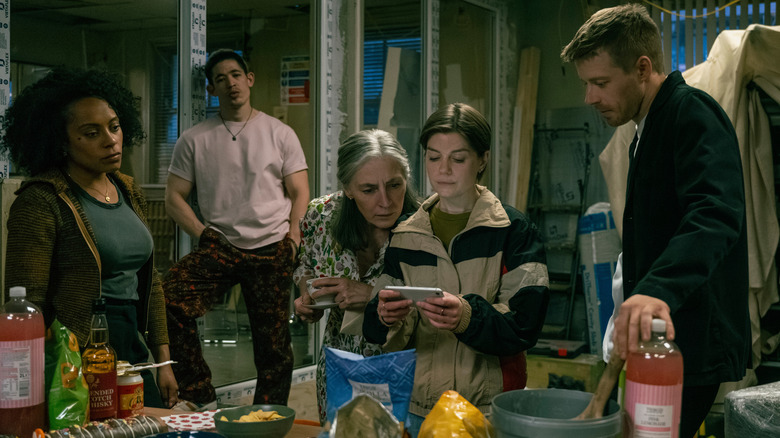 Lou, Roddy, Standish, Shirley y River miran un teléfono en Slow Horses
