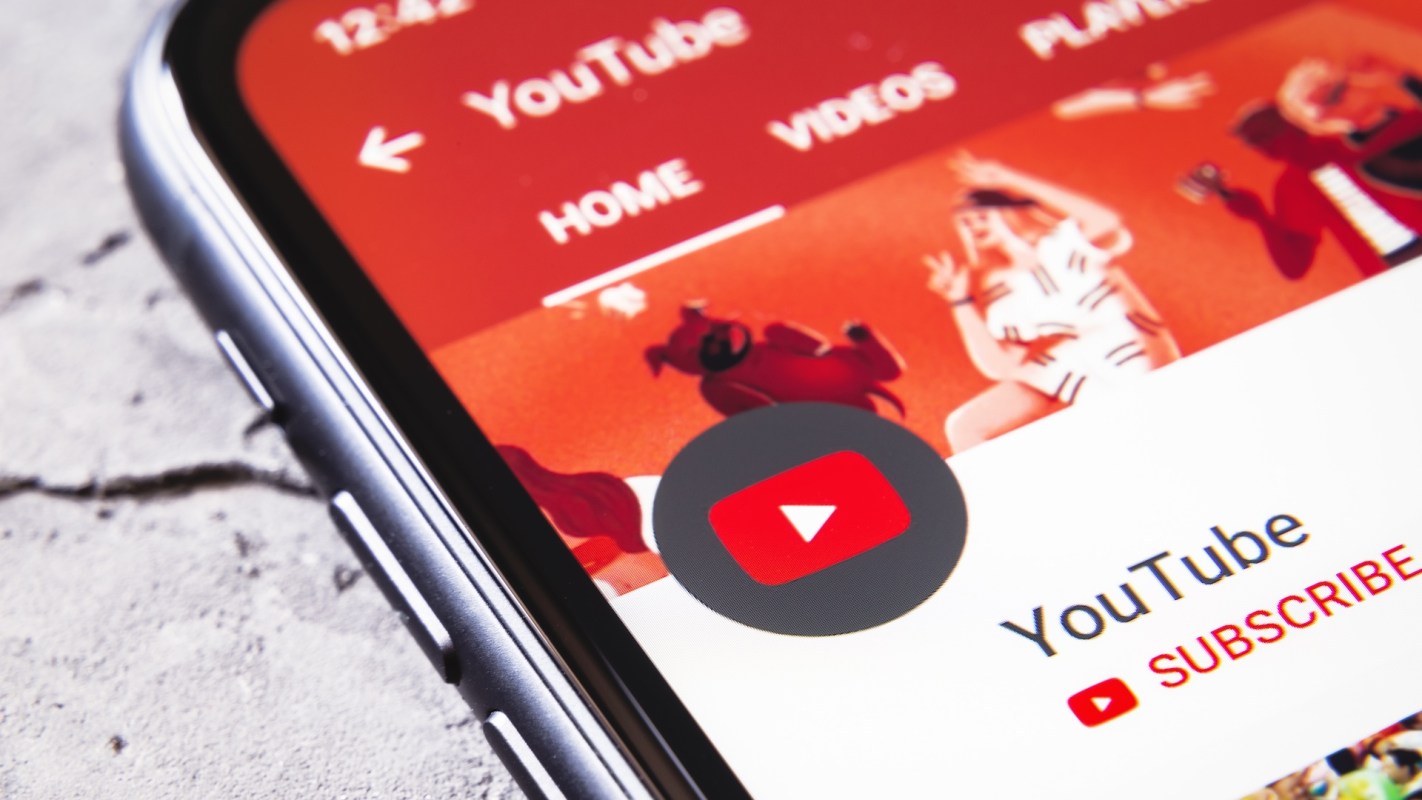 Primer plano de la pantalla de un teléfono inteligente que muestra la interfaz de la aplicación YouTube con un fondo colorido.