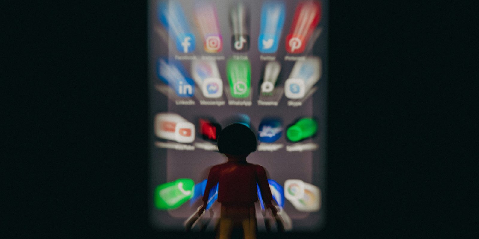 El 60% de los vídeos de TikTok son de IA; 21% de los de YouTube | La imagen muestra un personaje de robot de juguete frente a un conjunto borroso de íconos de aplicaciones.